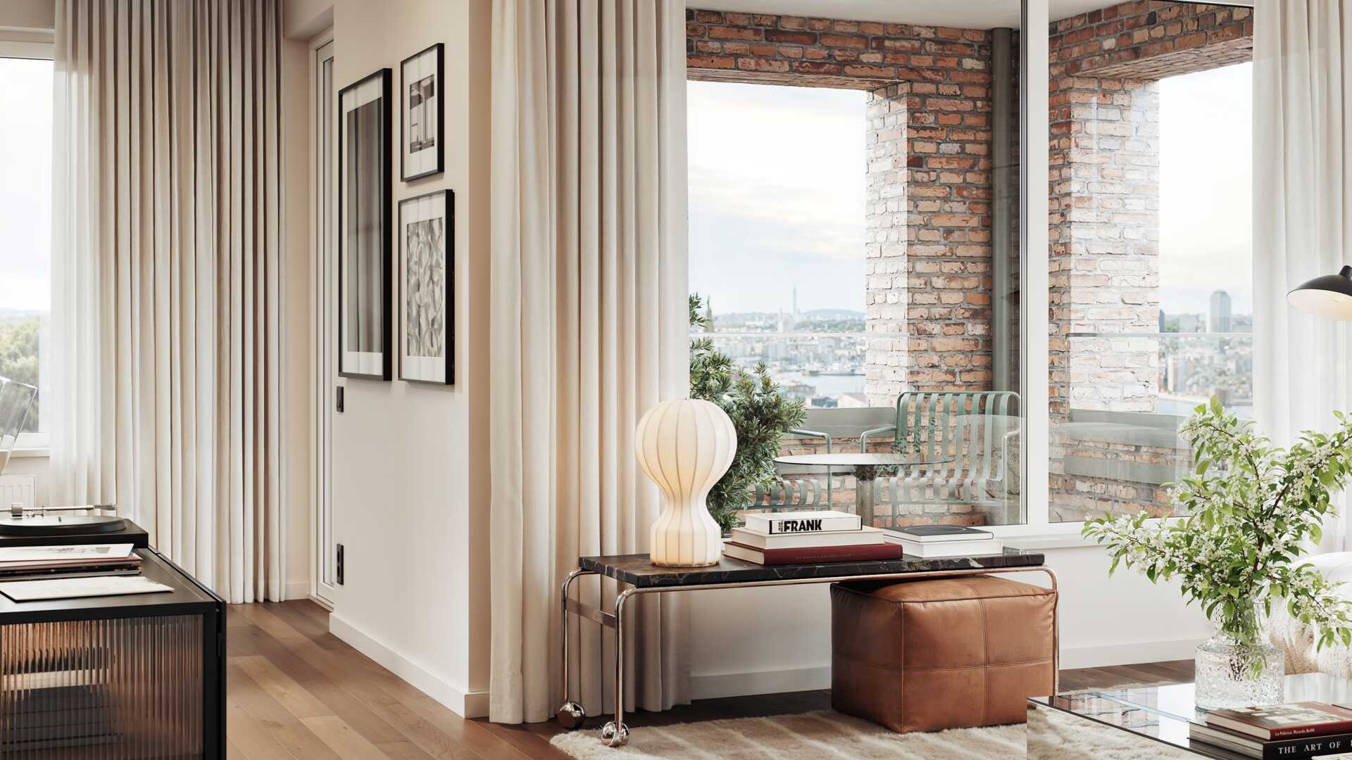 Ljust och modernt vardagsrum med stora fönster och utsikt över stadens skyline, inrett med konstverk på väggarna, en retro lampa och en läderpuff