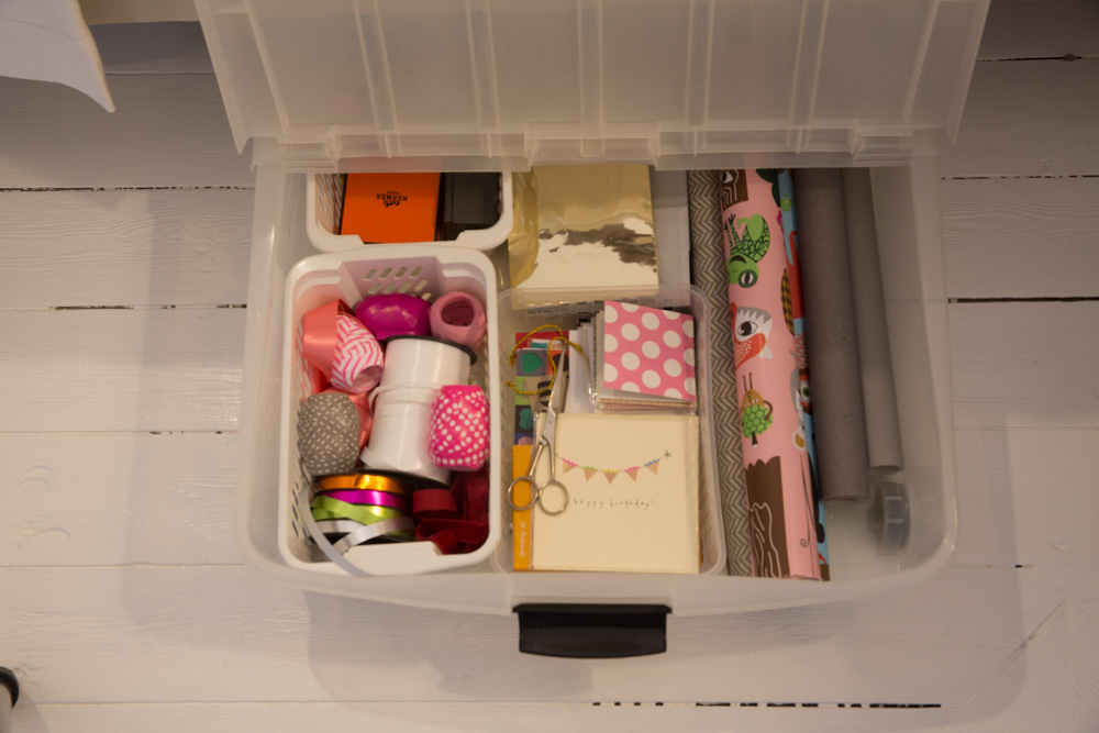 Plastlåda med olika presentinslagningstillbehör som färgglada band, kort och presentpapper
