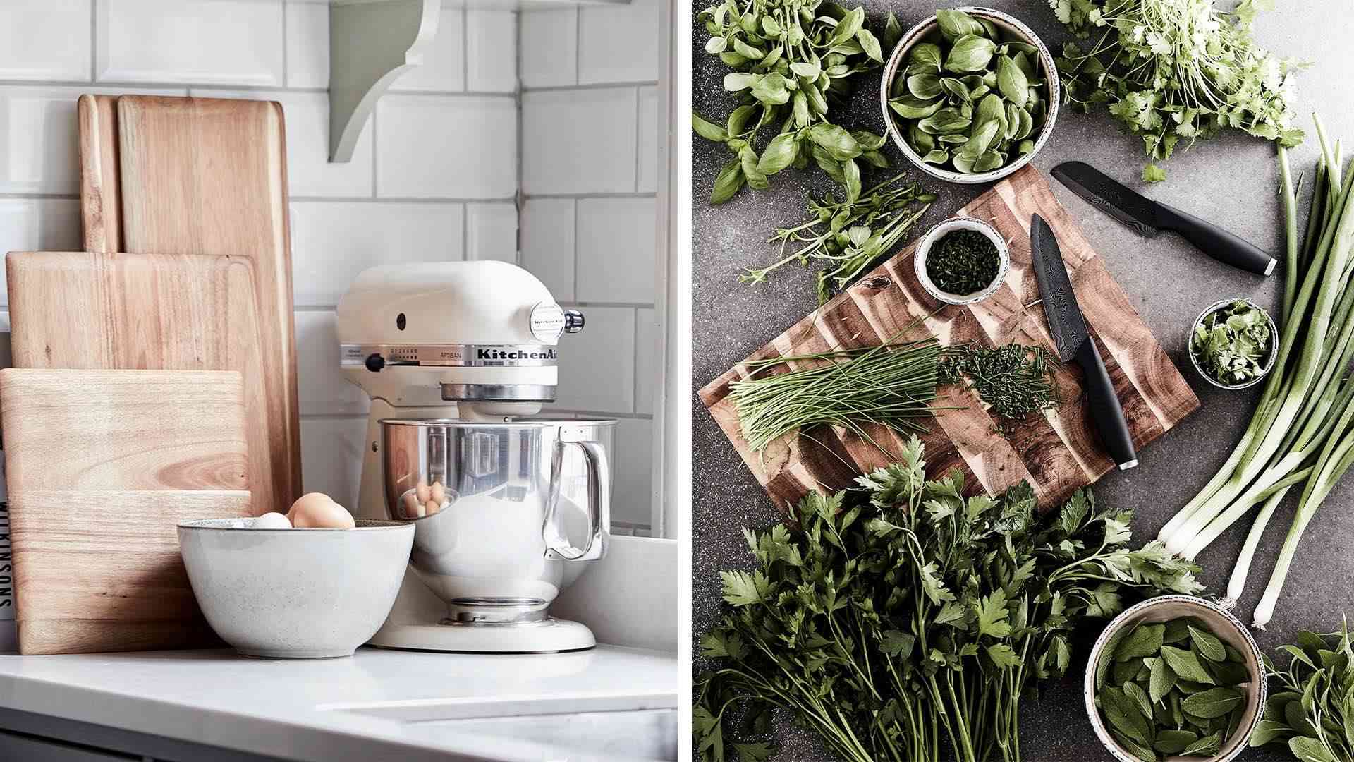 Köksbänk med skärbrädor, vit mixer och skål med ägg. Färska örter och knivar på en skärbräda