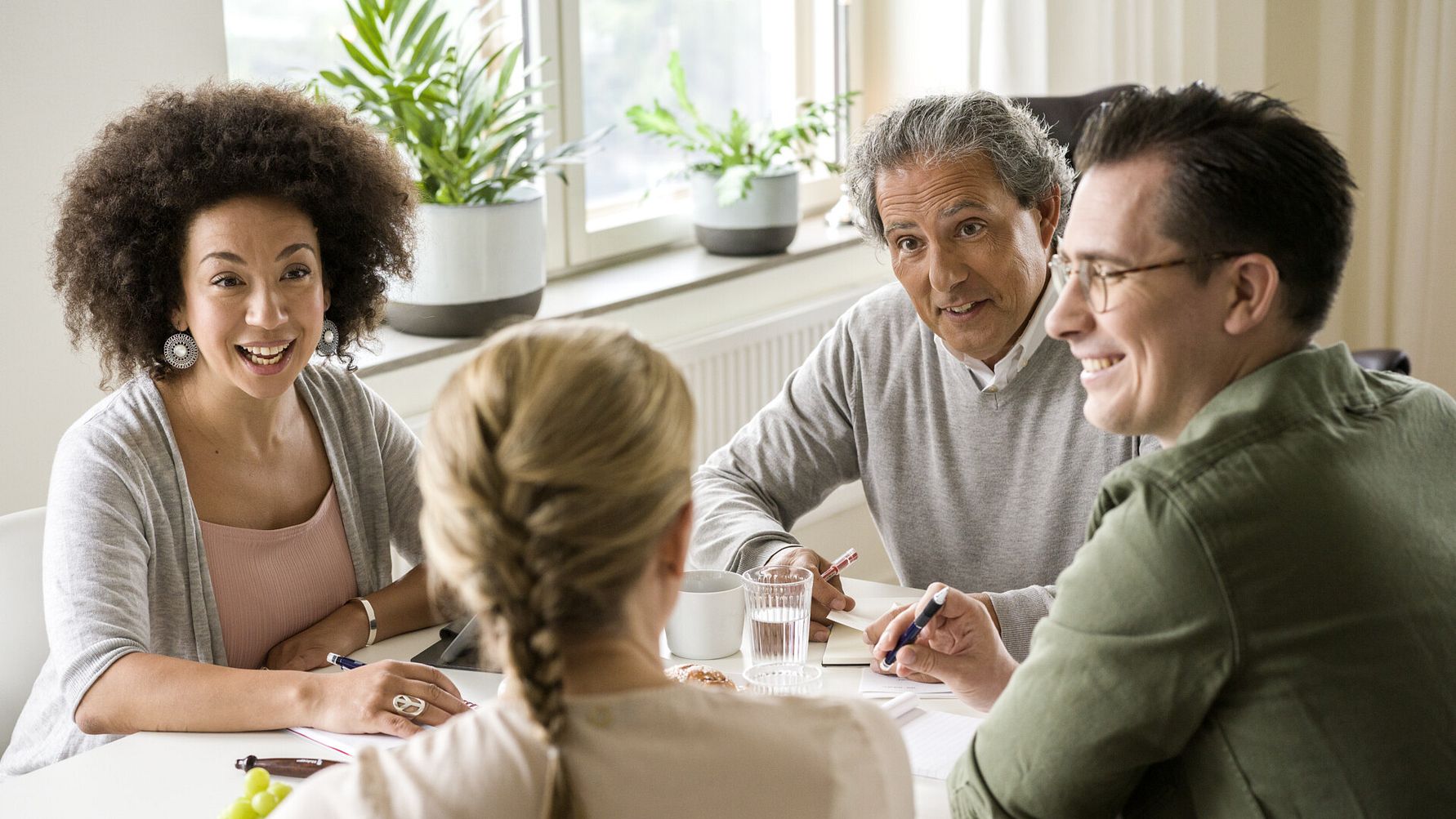 Fyra personer sitter runt ett bord i ett möte inomhus
