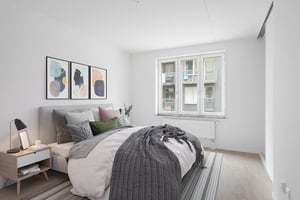 Inflyttningsklar lägenhet med sovrum, dubbelsäng, nattduksbord och stora fönster