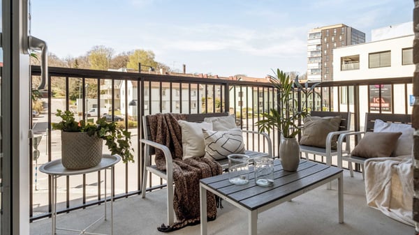 Balkong med soffgrupp, soffbord och utsikt över bostadshus