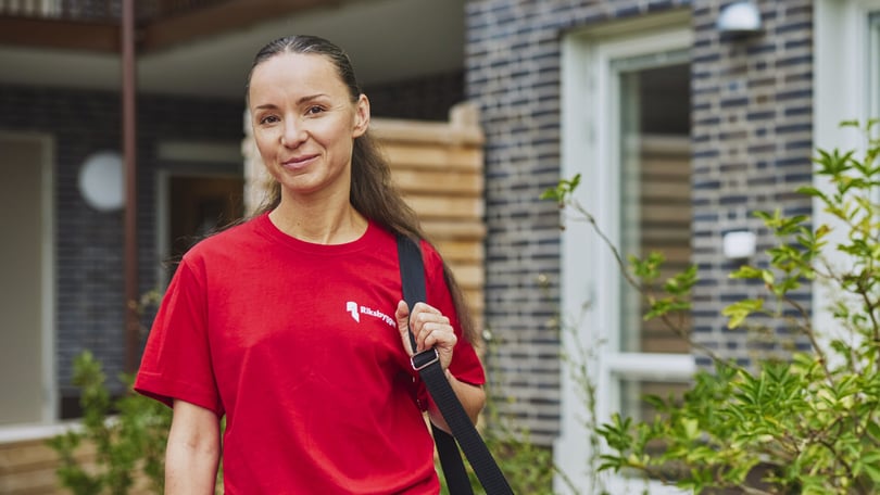 Kvinna klädd i röd tröja med Riksbyggens logotyp på